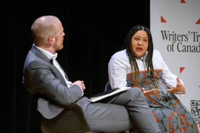 Zilla Jones speaks on stage next to the moderator. 