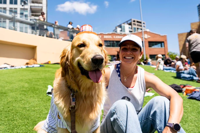 Photo of a Padres fan sitting next to their dog in Gallagher Square at Bark at the Park.