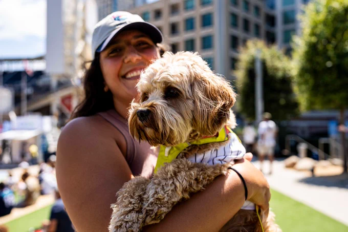 Photo of a Padres fan holding their dog in Gallagher Square at Bark at the Park.