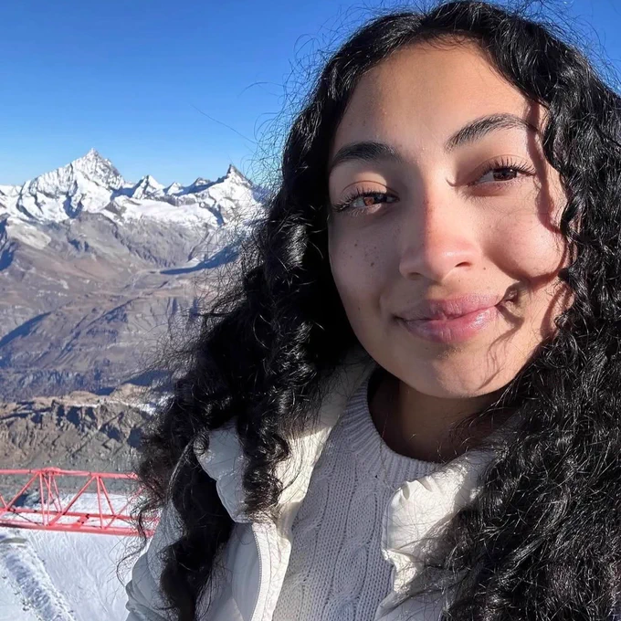Psychology major Valeria Aguayo smiles for a selfie with snow-capped mountains in the background.