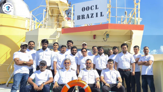Crew members of OOCL Brazil posing together on the vessel deck under clear daylight skies.