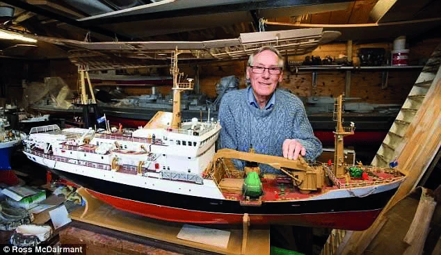 Lachie Stewart in a workshop displaying a large, detailed model ship on a wooden table.