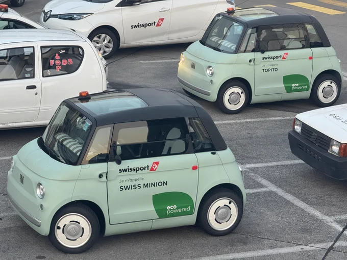 Two swissport small electric car in light green with a black roof. On the side it says „Je m‘apelle Swiss Minion“ on the first car, the second one is named „Topito“.
