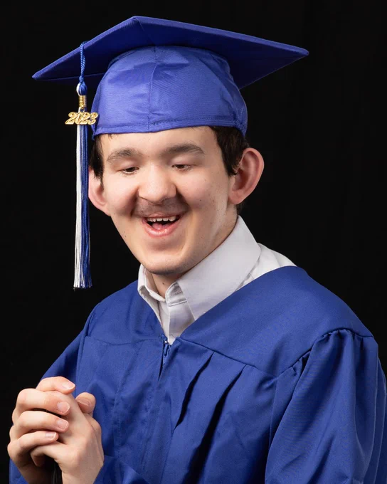 Matteo smiles in a blue graduation cap and gown