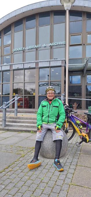 Timmy Mallet with his bike sitting on the balls outside Orkney Library and Archive