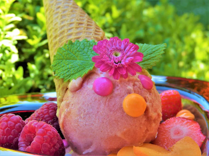 Ice cream cone decorated with fruit, smarties and a pink flower