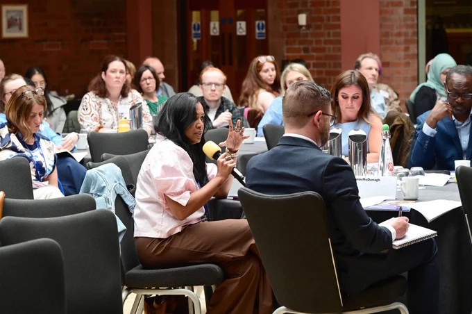 Attendees at the Ending Racism, advancing equality conference sitting with one attendee holding a microphone asking a question