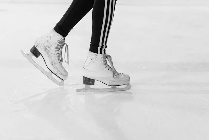 Close-up of ice skater's legs in action on an ice rink in monochrome.