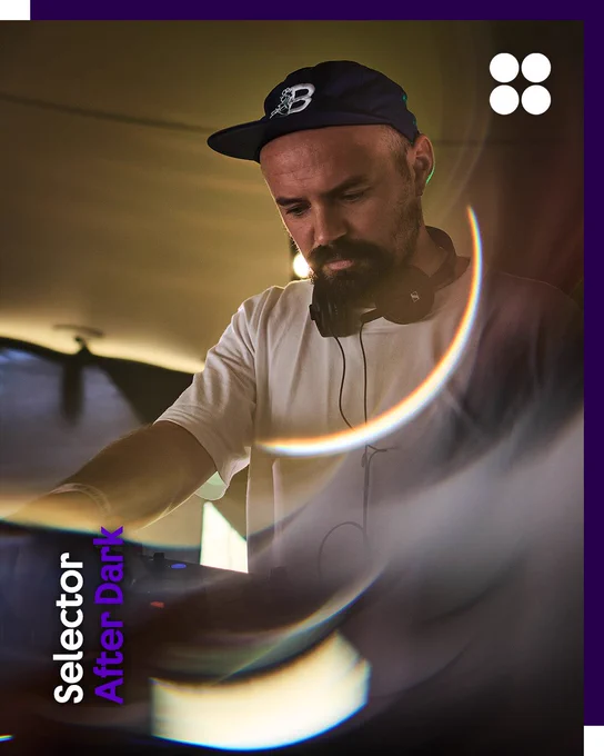 Rhys Baker, a bearded DJ performs indoors wearing a white T-shirt, black cap, and headphones around his neck, lit by warm ambient lighting and circular lens flare effects. The Selector Radio logo appears vertically in the bottom left corner alongside the name “After Dark” in purple text, while the British Council logo (four white circles) is in the top right. The border is dark purple.