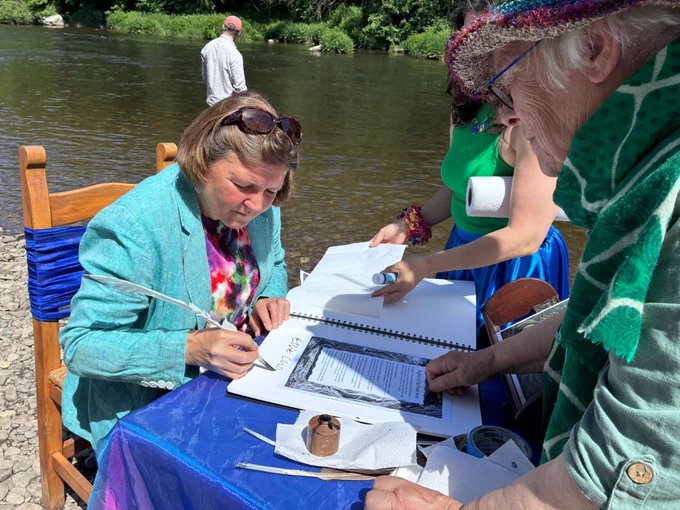 Ellie signing the charter by the riverside