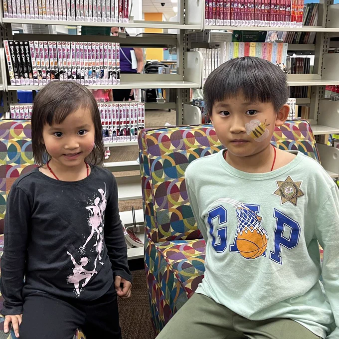 Two kids sitting with face paint.