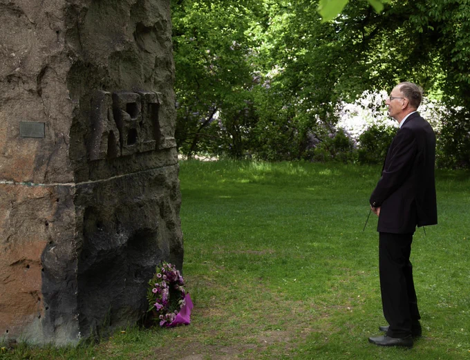 Abel Prize winner Gerd Faltings standing in front of a monument to Abel, with a purple wreath on the floor.