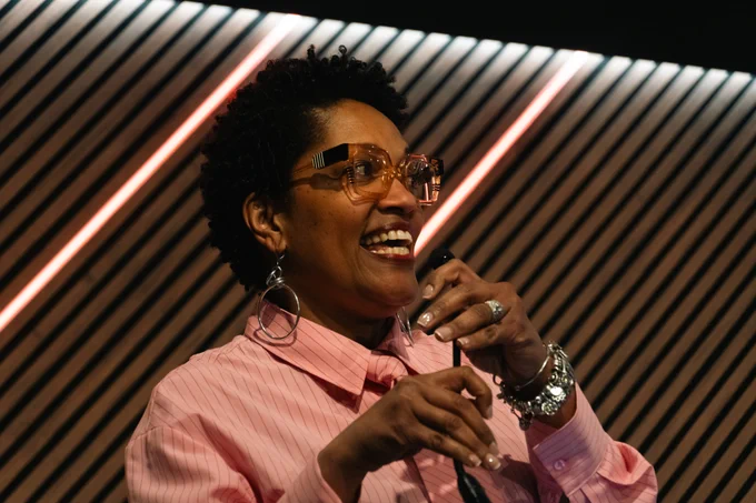 A candid photo of Dēmos president Taifa Smith Butler at an event holding a mic and smiling while speaking