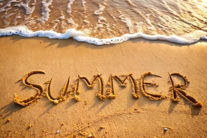 Image of a beach with "summer" carved into the sand
