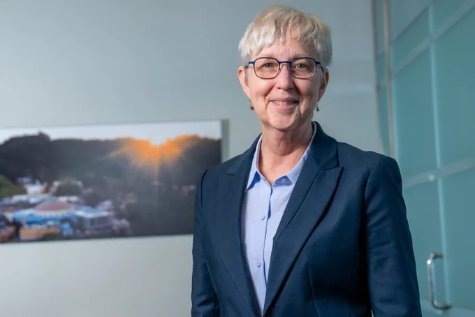 Katherine Yelick standing in front of a photo of Berkeley Lab