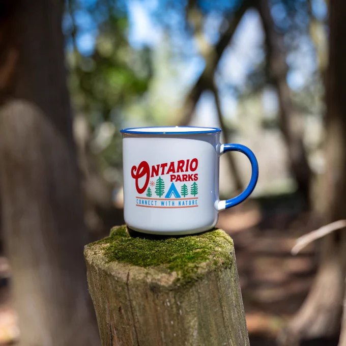 A white mug with "Ontario Parks" in red writing and the slogan "Connect with Nature" placed under green tree and a blue tent icon.
