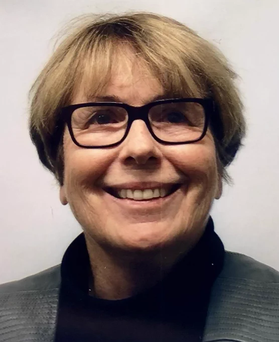 Smiling person with short blonde hair wearing glasses.