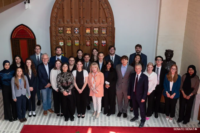 A group poses for a photo inside the Senate of Canada Building.