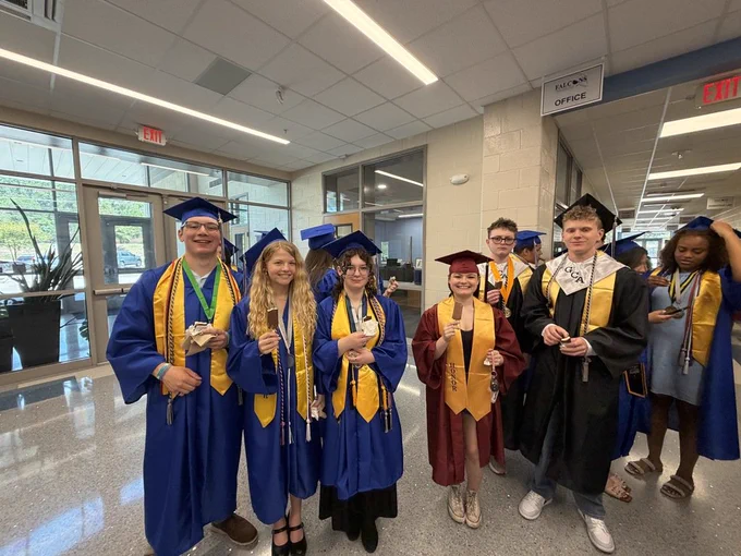A group of seniors stand together smiling at the camera and holding ice cream in their hands after the senior walk through.