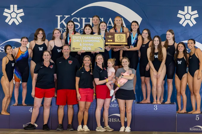 Blue Valley West Girls Swim & Dive posing with the 6A state championship trophy in front of a KSHSAA backdrop.