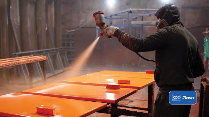 Worker spray painting in a workshop with the CDC and NIOSH logos