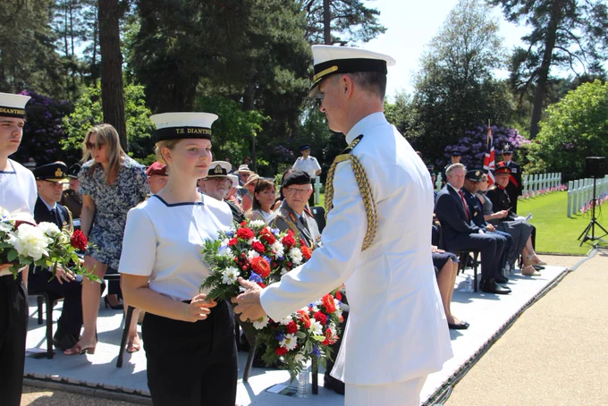 The U.S. Defense Attaché takes a wreath passed to him by a cadet at Brookwood American Cemetery.