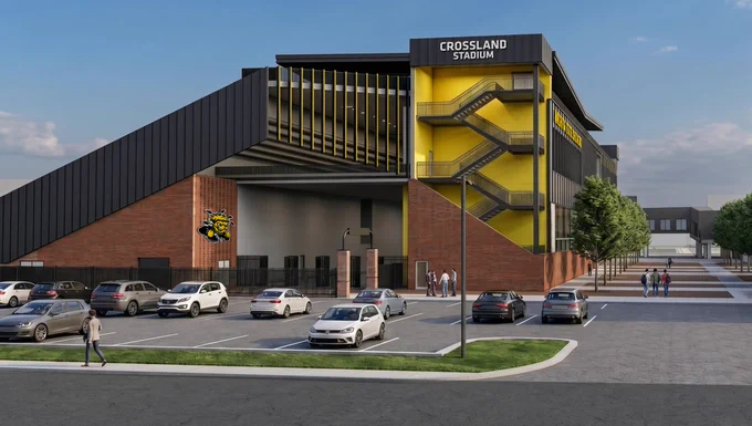 Front view of Crossland Stadium with prominent signage. The building features a modern design with red brick and a striking yellow staircase on the exterior. Several parked cars and a few people are visible in the foreground on a sunny day.