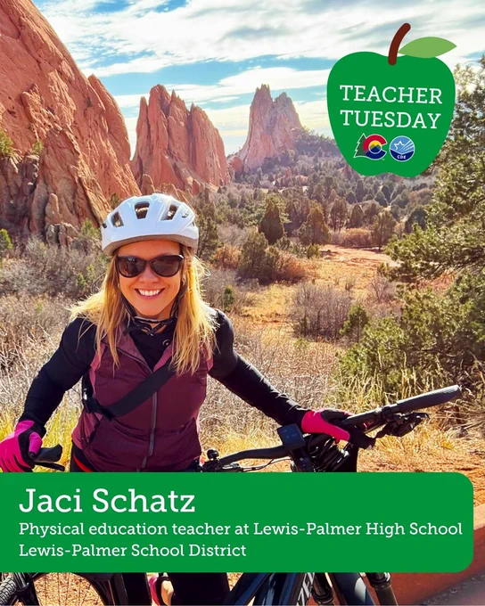 A person wearing a helmet and sunglasses is standing with a bicycle in a scenic outdoor area with large red rock formations. The person is smiling and dressed in outdoor gear. The image features a banner for "Teacher Tuesday" from Lewis-Palmer School District.
