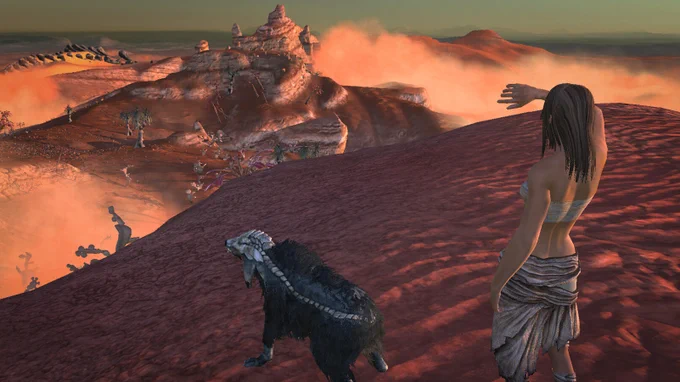 A long-haired character wearing a chest wrap and a wrapped skirt looks out on a desert view in the evening light. In the distance there's a settlement of some kind. Next to the character is a dog of some kind.