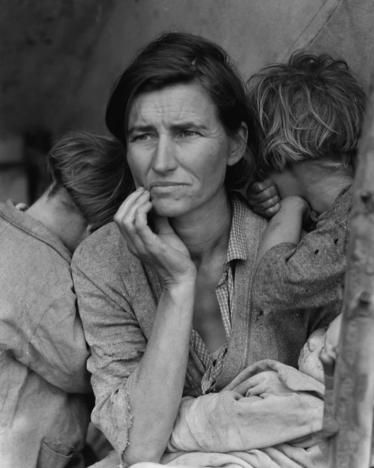 Dorothea Lange's famous "Migrant Mother" photograph features a mother holding a baby. Small children are leaning on each of her shoulders with their faces turned behind her, away from the camera. Their clothes are tattered. They are sitting under a lean-to tent structure in the middle of an empty field. The mother wears a look of concern.