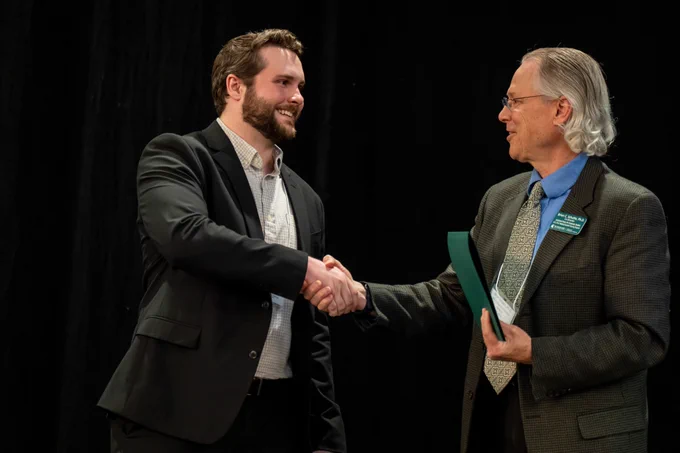 Michael Wischer and Brian Schutte shake hands as Michael accepts his award for his poster presentation. 
