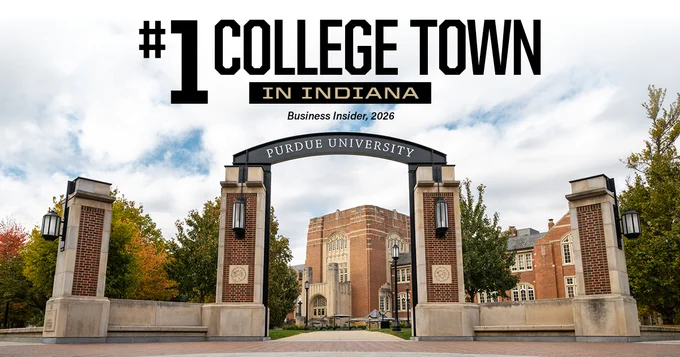 Entrance to Purdue University featuring an archway with the university's name. The Purdue Memorial Union building and trees are visible in the background. The image includes text stating "#1 College Town in Indiana, Business Insider, 2026."