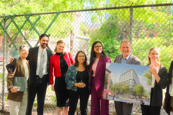 Standing with Mayor Mamdani and community leaders holding up a visual display of an upcoming development.