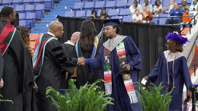 A graduate shakes hands with the superintendent. 