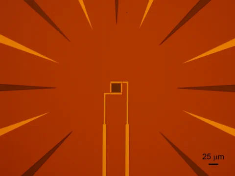 An abstract image with an orange background featuring radial lines extending outward from a central point. In the center, a geometric shape resembling a square is connected to two vertical lines. A scale marker at the bottom right corner indicates 25 micrometers.