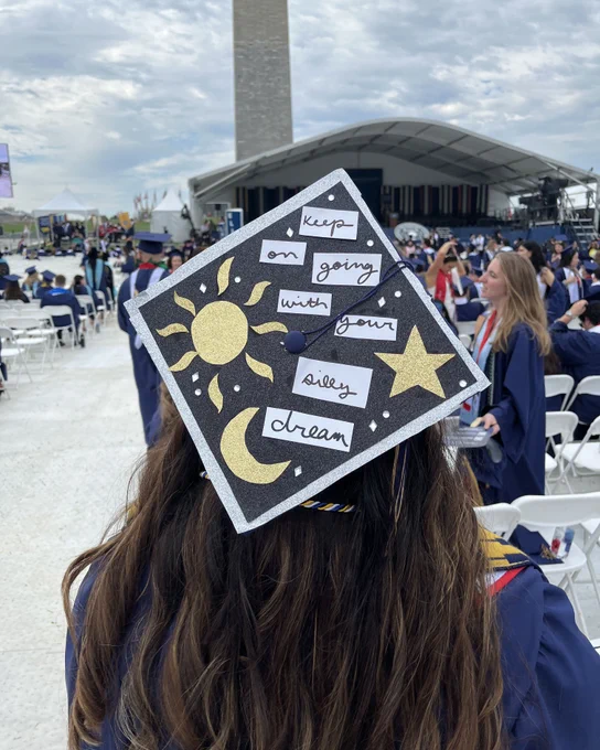 A graduate wearing a cap that reads “keep on going with your silly dream.”
