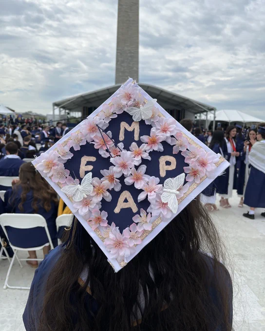 A graduate wearing a cap that reads “M.F.A.P.”