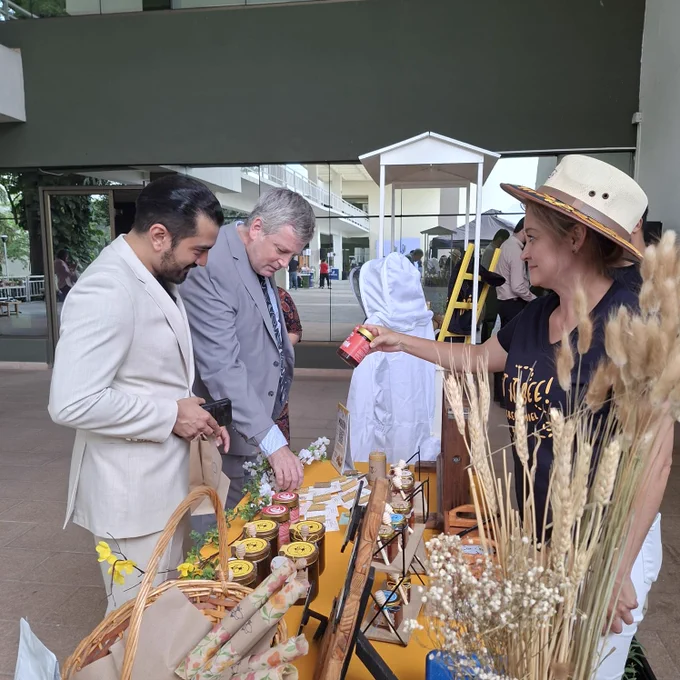 People viewing and receiving an explanation about honey products at a display booth