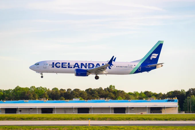 An Icelandair aircraft on final approach at BWI Thurgood Marshall Airport with a cargo building in the background.