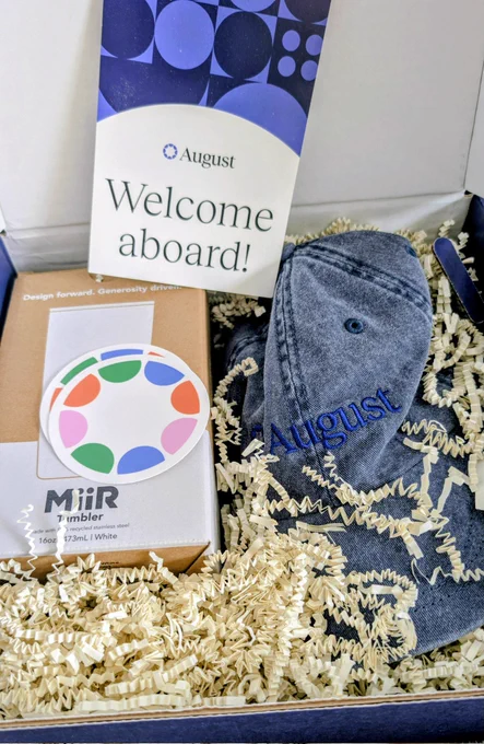 August welcome kit with a tumbler, stickers, and a hat