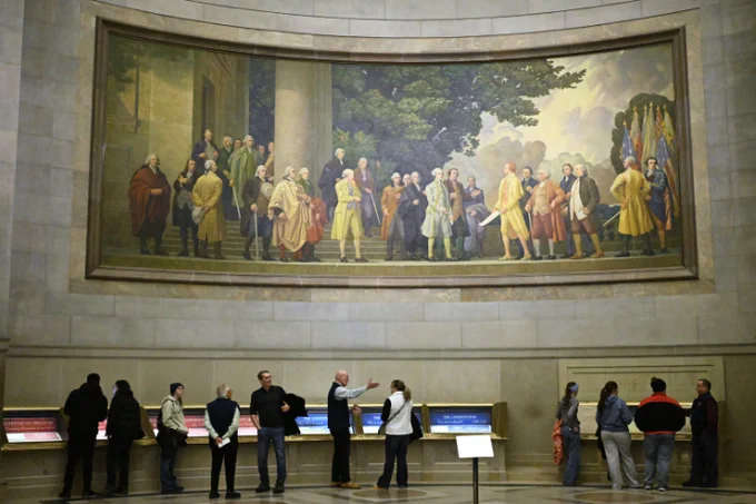 A large wall mural showing the signing of the Declaration of Independence is seen over visitors at the National Archives, Jan. 29, 2026, in Washington. John McDonnell, Associated Press.