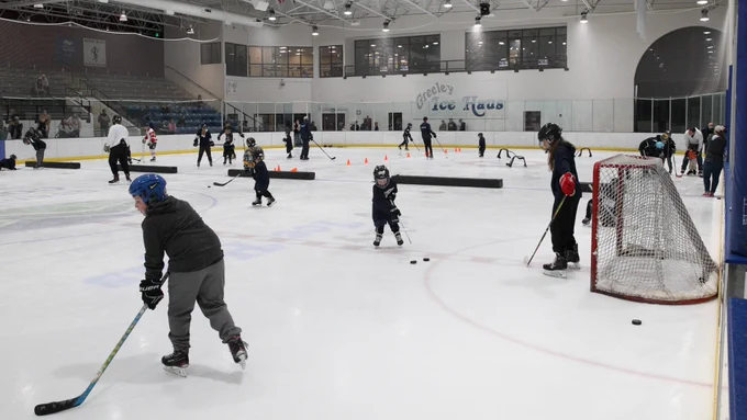 Young hockey players try shooting the puck in the goal.