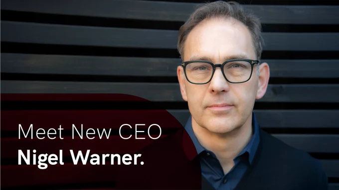Headshot: Nigel Warner, a man with short brown hair wearing dark-framed glasses and a navy shirt. In the bottom left corner is a red overlay with white text reading: 'Meet New CEO Nigel Warner.'