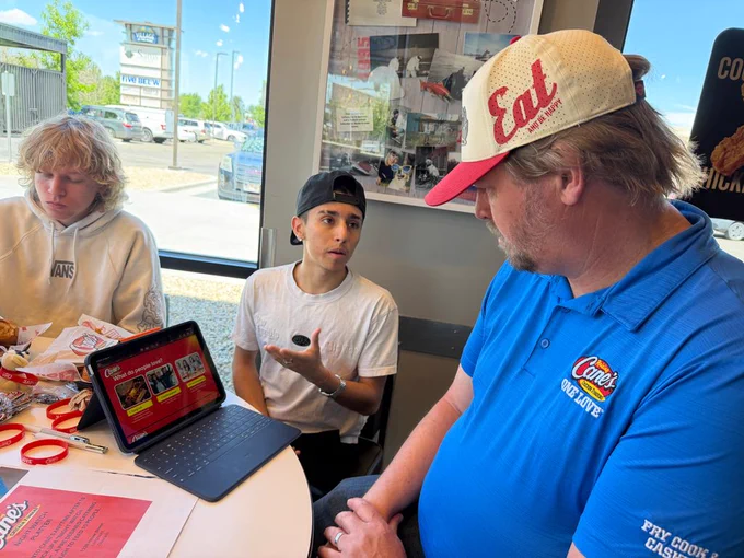 A student presents to a Cane's employee.