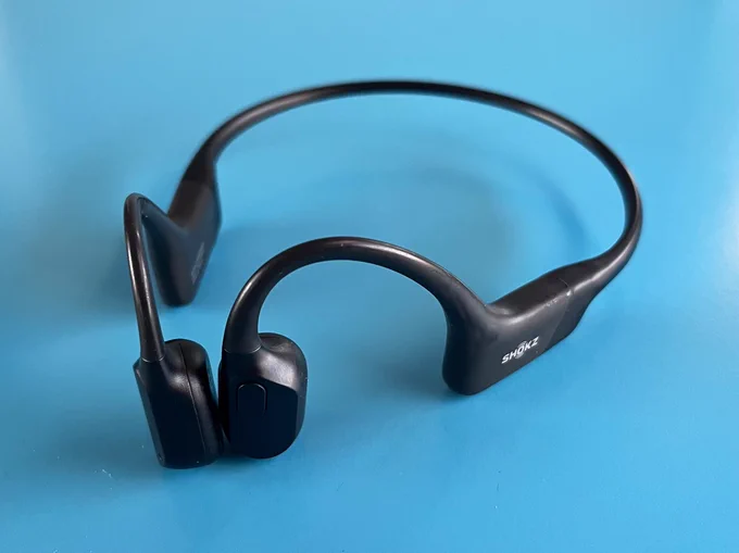 A set of black Shockz Openrun headphones on a blue background