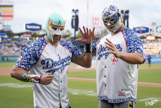 A photo of Máscara Dorada and Xelhua posing on the field before saying, “It’s Time For Dodger Baseball.”