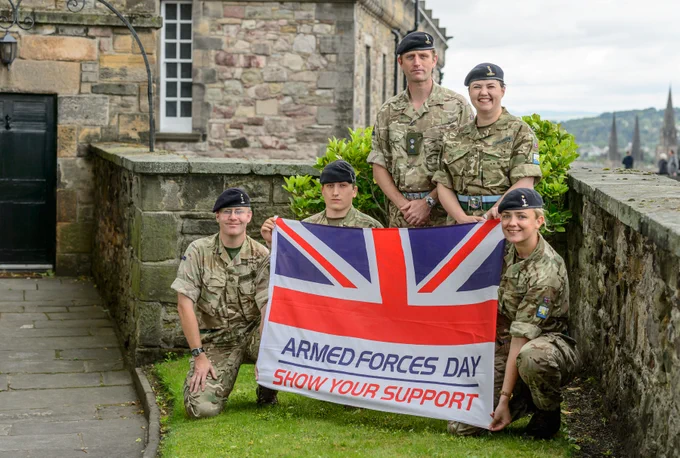 Uniformed personnel hold an Armed Forces Day flag.