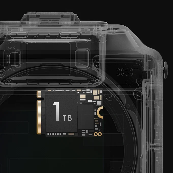 Detalle técnico de una cámara Hasselblad X2D II 100C con vista en transparencia del cuerpo, mostrando componentes internos y un módulo de almacenamiento de 1 TB en el interior, sobre fondo negro