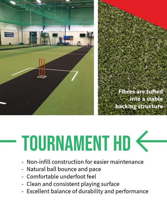Indoor cricket pitch with green and black synthetic turf and orange wickets under a high ceiling with netting.