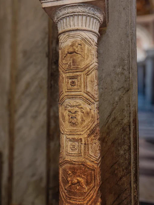 LACUNAR COLUMN, C2 CE. VATICAN MUSEUMS

Here we see an unusual Roman storied column carved in high relief. The marble shaft is divided into a vertical grid of interlocking hexagonal medallions, an eccentric design choice likely mimicking luxury metalwork or molded stucco ceilings. Inside these geometric frames are very fine carvings: a galloping horse at the top, a wildly-tousled bearded face in the middle, and a bull lower down. Discovered in 1771 by Gavin Hamilton at the Villa of Gallienus along the Via Appia, it was probably part of a set of four framing an œcus or reception room. Since Roman builders usually preferred standard fluting or simply a smooth marble surface, this bespoke survivor is incredibly rare. Restored in the eighteenth century, it now stands proudly in the Sala degli Animali, having narrowly escaped being shipped off to an English country estate by the enterprising excavator.